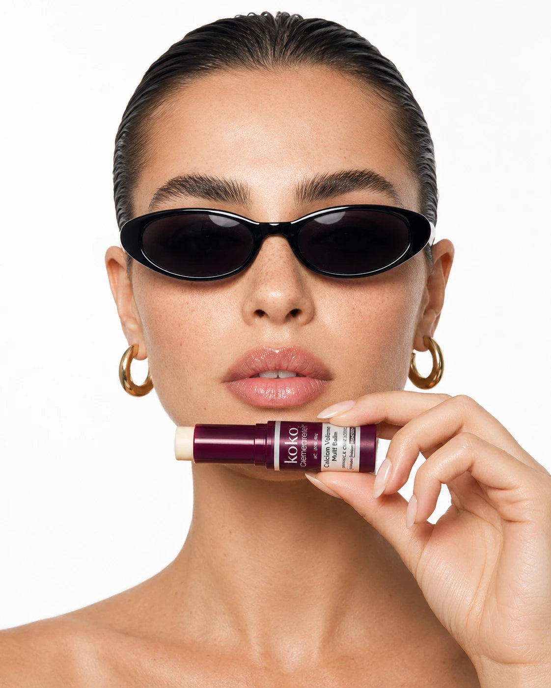 Model wearing black sunglasses and holding Koko Calcium Multi Balm