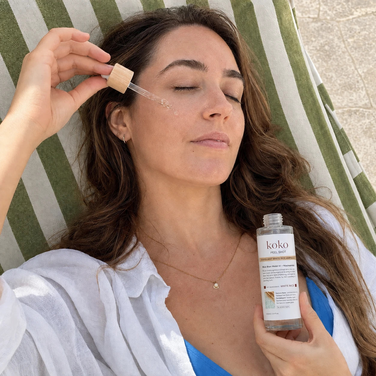 Koko campaign: Glow Rice Ampoule on a striped lounger