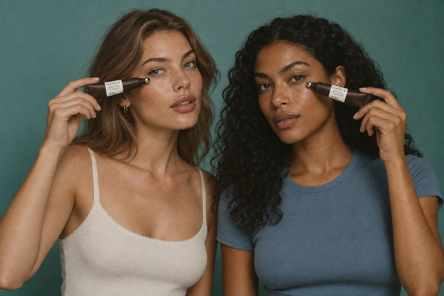 Two women holding Koko eye cream beneath their eyes